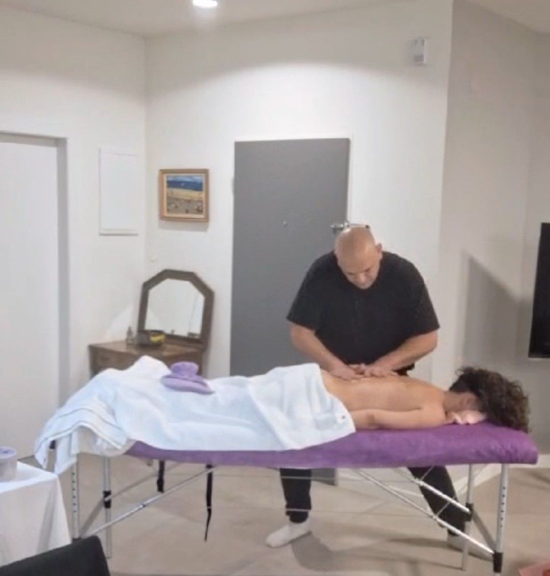 מטפל מבצע טיפול עיסוי לגב המטופלת על שולחן טיפול